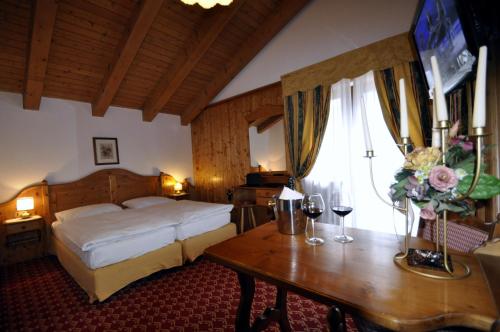 a bedroom with a bed and a table with wine glasses at Hotel Al Forte in Arabba