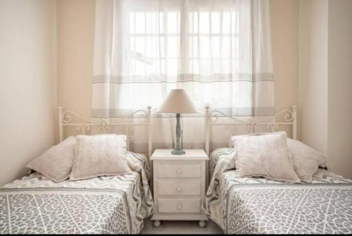 a bedroom with two beds and a lamp on a night stand at Apartamento El Mirador del Cantil in Isla Cristina