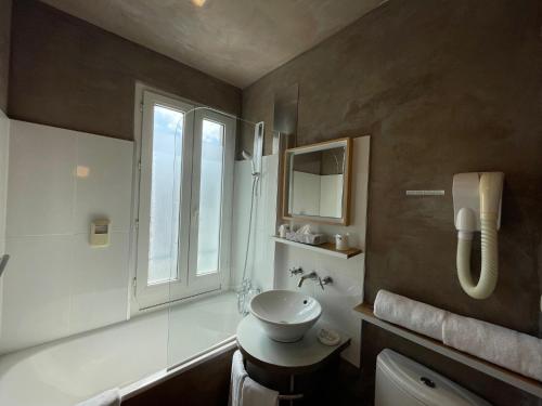 un bagno con lavandino, water e finestra di Adonis Cottage la Baule a La Baule
