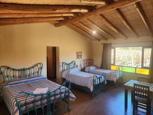 a room with two beds and a table and windows at El Hornero in Tilcara
