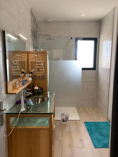 La salle de bains est pourvue d'un lavabo en verre et d'une douche. dans l'établissement Maison Benclé, à Vaux-sur-Mer