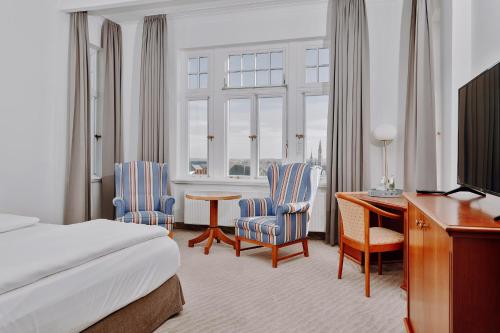 a hotel room with a bed and a desk and chairs at Seehotel Borkum in Borkum