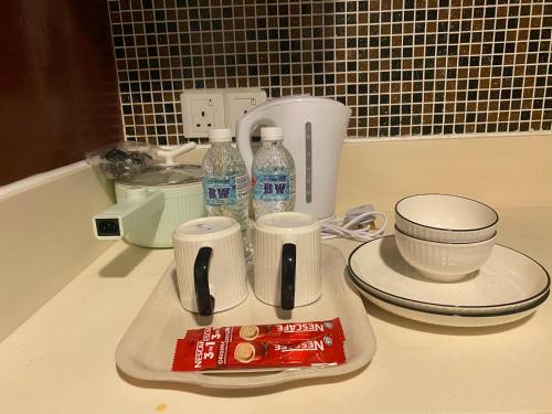a counter with a tray with cups and bottles of water at KK City Centre SCSP 2pax Urban Suites 亚庇市中心民宿 in Kota Kinabalu