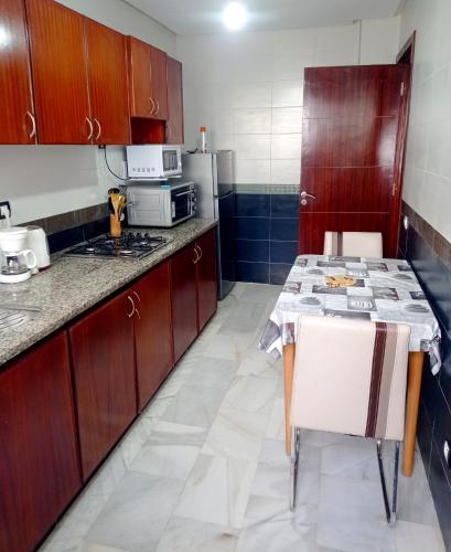 Oulad YakoubにあるAppartement meublé à 4 min de Technopolis résidence SALIMAのキッチン(木製のキャビネット、テーブル付)