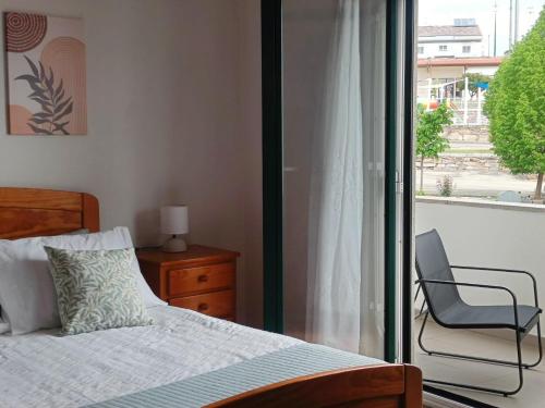 a bedroom with a bed and a chair and a window at Apartamento Luminoso em Miranda in Miranda do Douro