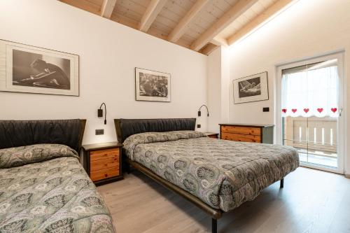 a bedroom with two beds and a window at Casa Pini By Go new location in Moena
