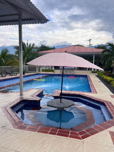 a swimming pool with an umbrella and a table at Finca Hotel Villa el Ocaso Huila in Rivera