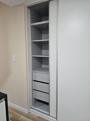 a closet with white shelves in a room at Alquiler Temporario Rosario 24 in Rosario