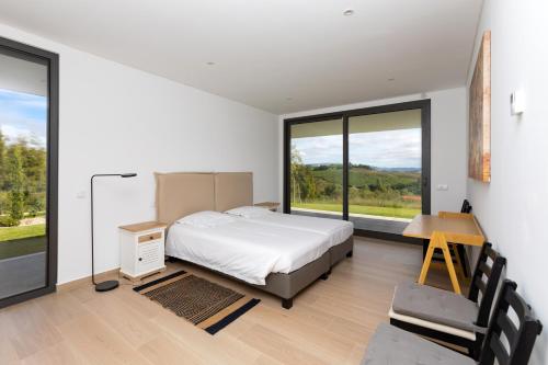 Un dormitorio con una cama, un escritorio y ventanas. en Casa Barbónica piscina privada, en Bairro do Lobo