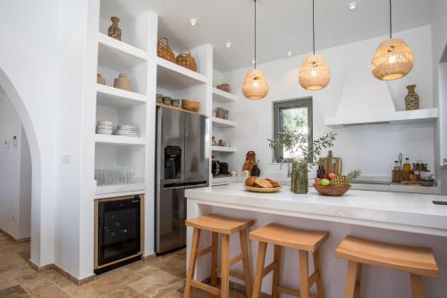 a kitchen with white cabinets and a counter with stools at Villa Elaia in Afantou