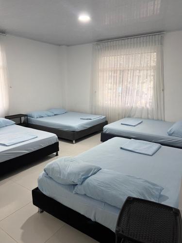 a room with three beds and a window at Finca Hotel Villa el Ocaso Huila in Rivera