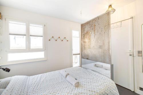 une chambre blanche avec un lit et un miroir dans l'établissement GuestReady - A glamorous sight over the city, à Paris