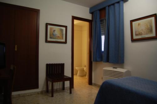 a bedroom with a bed and a chair and a window at Hotel Marina Victoria in Algeciras