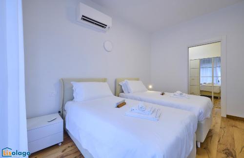 two beds with white sheets in a room at Blue Heaven in Lierna