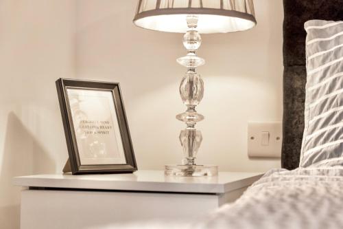 a bedside table with a lamp and a picture at Large One Bedroom Apartments Southsea Sleeps 3 - Free Parking in Portsmouth