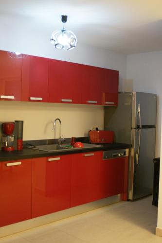 La cuisine est équipée de placards rouges et d'un réfrigérateur en acier inoxydable. dans l'établissement Totem Sud, à Arcachon