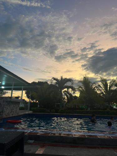 a swimming pool with a sunset in the background at Finca Hotel Villa el Ocaso Huila in Rivera
