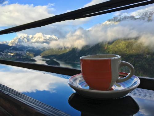 a cup of coffee sitting on a plate in front of a window at Dolomiti in Pieve di Cadore