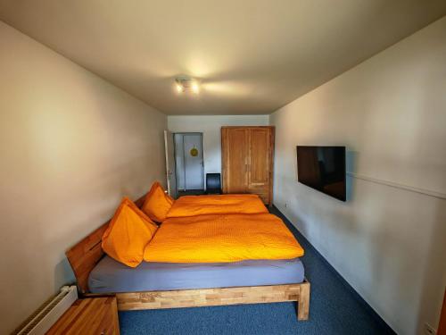 a small bedroom with a bed with an orange blanket at 4 Zimmer 115m2 Gartenwohnung an der Jakobshorn Talstation neben Wander- und Mountainbikeparadise in Davos