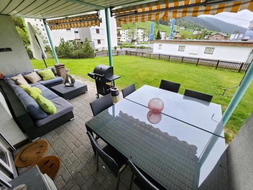 a patio with a table and a couch at 4 Zimmer 115m2 Gartenwohnung an der Jakobshorn Talstation neben Wander- und Mountainbikeparadise in Davos
