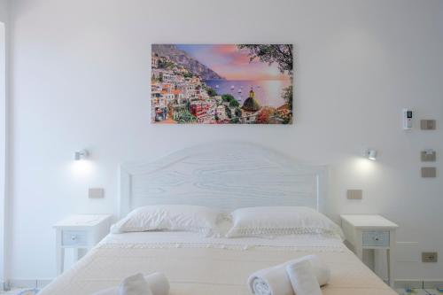 a bedroom with a white bed and a painting on the wall at LA CASA DEL CAPITANO furore amalfi coast in Furore