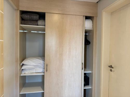 a closet with a wooden door and a bed at Destino Floripa Jurerê in Florianópolis