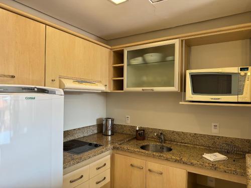 a kitchen with a sink and a microwave at Destino Floripa Jurerê in Florianópolis