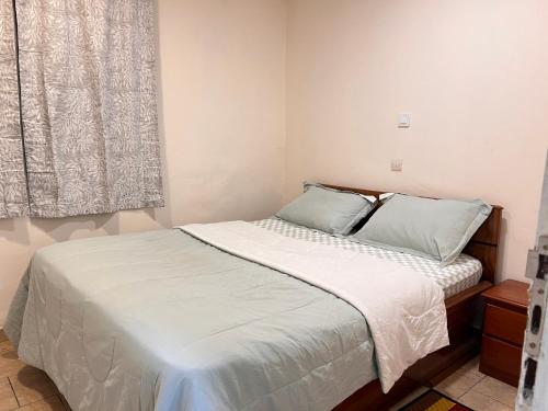 a bedroom with a bed with white sheets and a window at Tetsassi home in Yaoundé