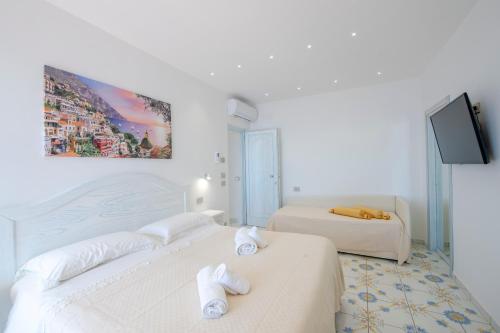 two beds in a white room with a tv at LA CASA DEL CAPITANO furore amalfi coast in Furore