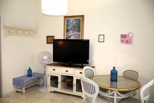 a living room with a tv and a table with chairs at La Graziella in Le Grazie