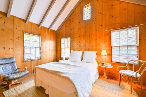 a bedroom with wooden walls and a bed and a chair at Walk to Amagansett Beach Cottage with Deck! in Amagansett