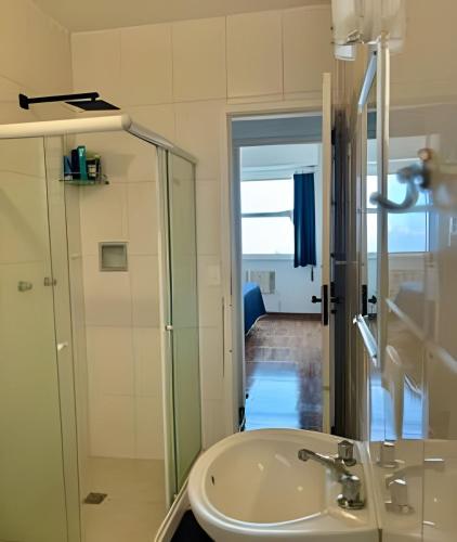 a bathroom with a sink and a glass shower at Vista deslumbrante e conforto em Ipanema in Rio de Janeiro