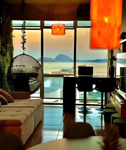 a living room with a couch and a desk in front of a window at Vista deslumbrante e conforto em Ipanema in Rio de Janeiro