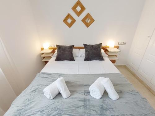 ein Schlafzimmer mit einem Bett und zwei weißen Hausschuhen in der Unterkunft Apartamento La Noria pie de playa Manilva in San Luis de Sabinillas