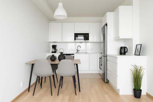 a kitchen with white cabinets and a table and chairs at City Home Finland Panorama Suite - New Luxury Suite with Own SAUNA, One Bedroom, Spacious Balcony with City Views and Great Location next to Nokia Arena in Tampere