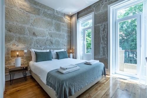 a bedroom with a large bed with a stone wall at ApartmentsPorto - Porto Dukes House in Porto