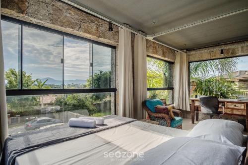 a bedroom with a bed and a large window at Estúdios completos na Praia de Imbituba - PRN in Praia do Rosa
