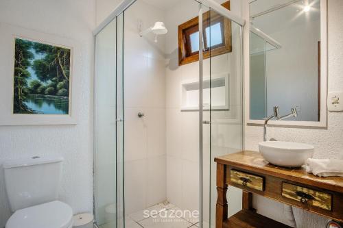 a bathroom with a glass shower and a sink at Estúdios completos na Praia de Imbituba - PRN in Praia do Rosa