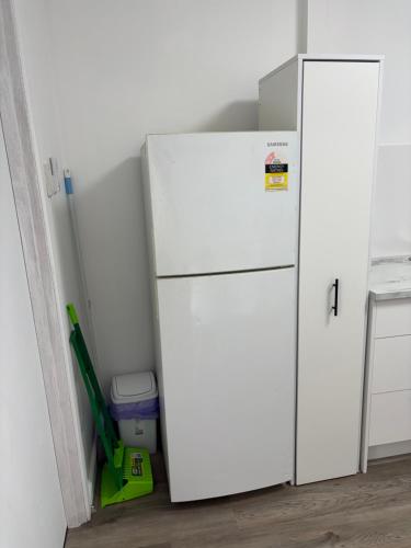 a white refrigerator in a room with a broom at Sunflower Homes- Peace and Joy in Para Hills