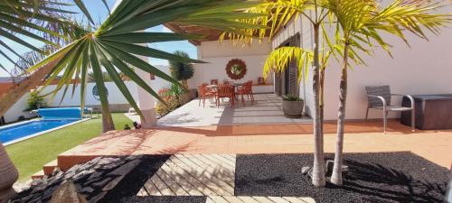a house with a patio with a table and a pool at Villa Del Corazon Salinas Golf in Caleta De Fuste