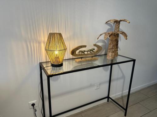 a glass table with a lamp and other items on it at Le Bohème - Appartement proche gare et commerces in Gisors