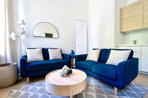 - un salon avec deux canapés bleus et une table basse dans l'établissement 3 pièces élégant - Clim Terrasse Parking - Plage, à Saint-Raphaël