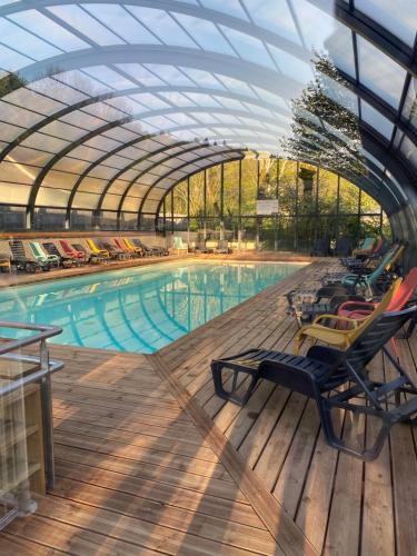 une piscine avec des chaises et un toit en verre dans l'établissement Mobil-home 3ch le Per Malou Camping Les Clarines, à La Bourboule