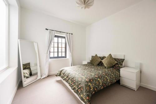 Un dormitorio blanco con una cama y un espejo. en The Old Post Office, en Norwich