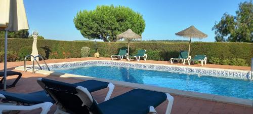 a swimming pool with chairs and umbrellas next to it at Quinta das AVES - Double Bedroom 1 in Odiáxere