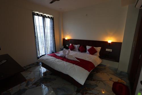 a bedroom with a large bed with red pillows at The Brij Vista in Mathura