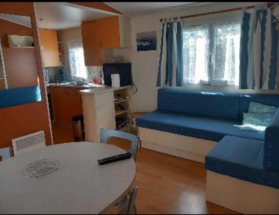 un salon avec une table et un canapé bleu dans l'établissement Mobil-home l'évasion, à La Bernerie-en-Retz
