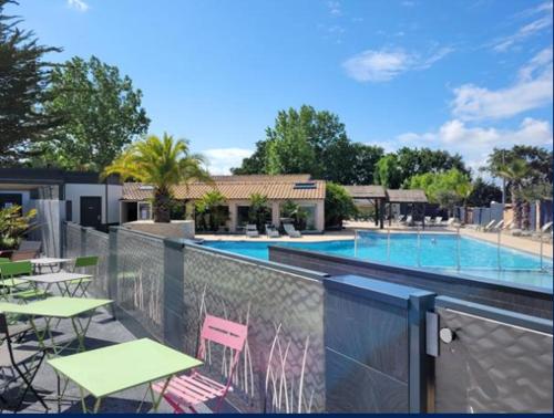 un balcon avec des tables et des chaises ainsi qu'une piscine dans l'établissement Mobil-home l'évasion, à La Bernerie-en-Retz