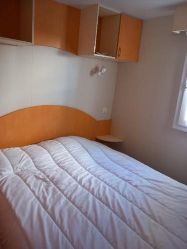 une chambre avec un lit blanc dans une pièce dans l'établissement Mobil-home l'évasion, à La Bernerie-en-Retz