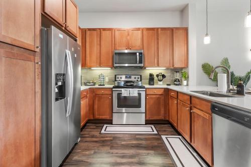 a kitchen with wooden cabinets and stainless steel appliances at Downtown Modern Elegance Suite with Free Parking, Pool, WIFI and a King Bed in Houston